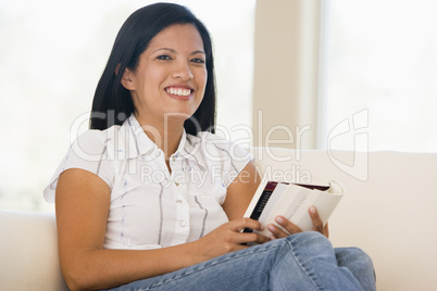 Woman in living room reading book smiling