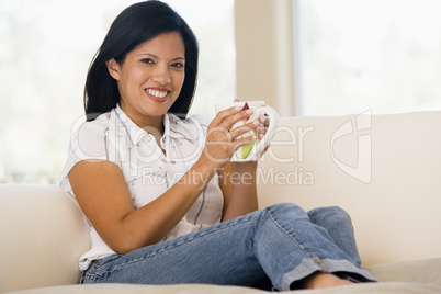 Woman in living room with coffee smiling