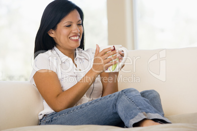 Woman in living room with coffee smiling