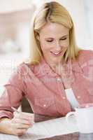 Woman in kitchen with newspaper and coffee smiling