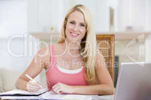 Woman in kitchen with newspaper and coffee smiling