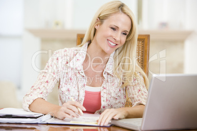 Woman in dining room with laptop smiling