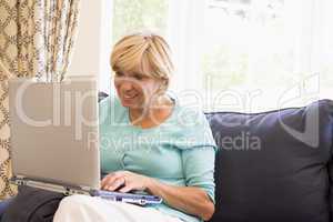 Woman in living room with laptop smiling