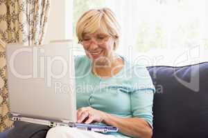 Woman in living room with laptop smiling