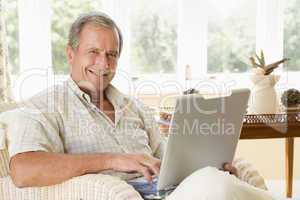 Man in living room with laptop smiling