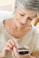 Woman using cellular phone indoors smiling