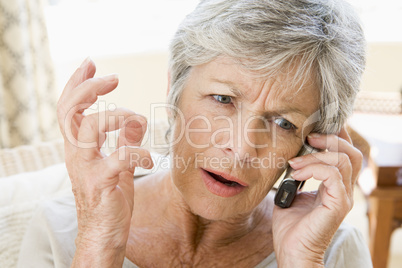 Woman indoors using cellular phone frowning