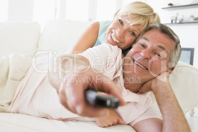 Couple in living room using remote control smiling