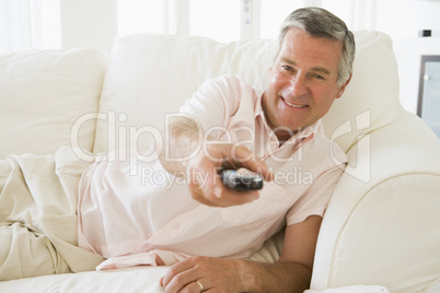 Man in living room using remote control smiling