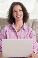 Woman in living room with laptop smiling