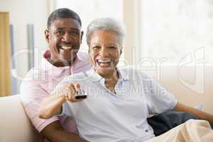 Couple in living room using remote control smiling