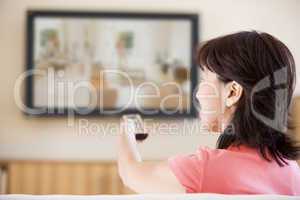 Woman watching television using remote control