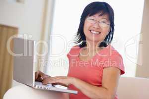 Woman in living room with laptop smiling