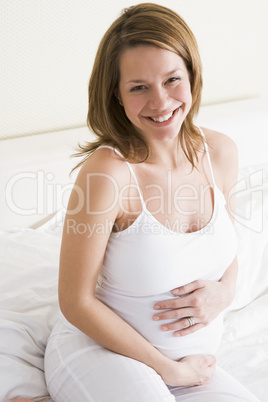 Pregnant woman sitting in bed smiling