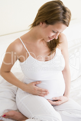 Pregnant woman sitting in bed smiling