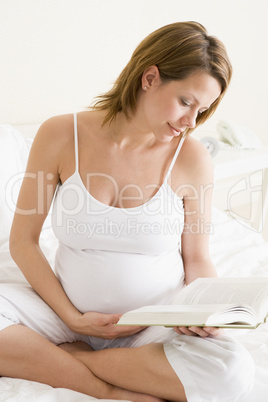 Pregnant woman in bedroom reading book