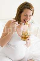 Pregnant woman in bed eating pickled eggs smiling