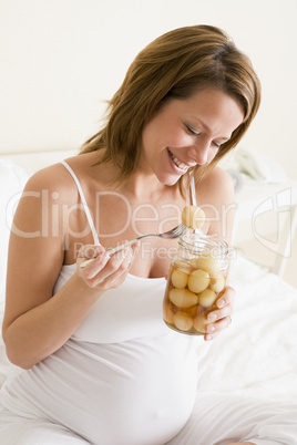 Pregnant woman in bed eating pickled eggs smiling