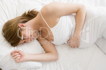 Pregnant woman lying in bed smiling