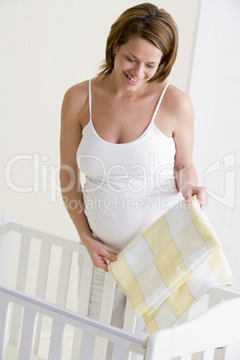 Pregnant woman setting up baby crib smiling