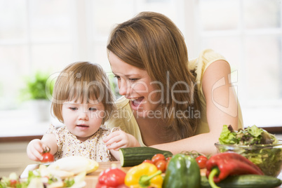 Mother and daughter in kitchen making a salad smiling