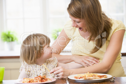 Pregnant mother with daughter touching belly eating French fries