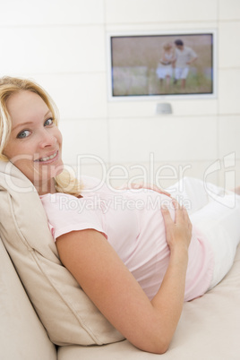 Pregnant woman watching television smiling