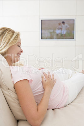 Pregnant woman watching television smiling