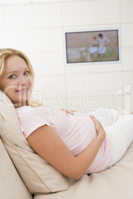 Pregnant woman watching television smiling