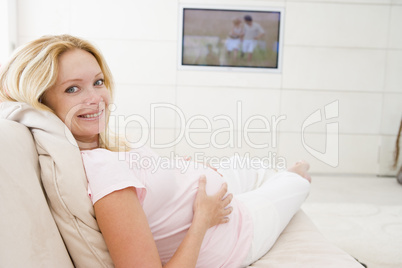 Pregnant woman watching television smiling