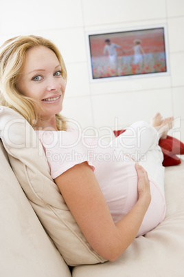 Pregnant woman watching television smiling