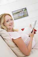 Pregnant woman reading magazine with television in background sm