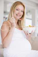 Pregnant woman with bowl of fruit salad smiling