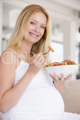 Pregnant woman with bowl of salad smiling