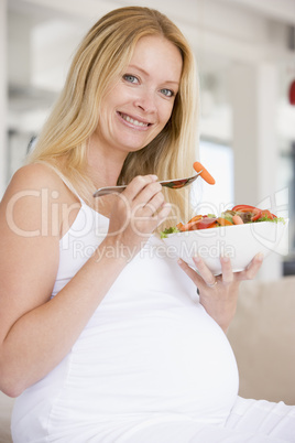 Pregnant woman with bowl of salad smiling