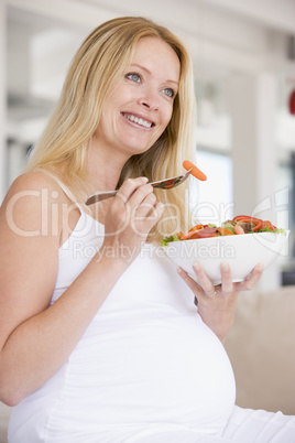 Pregnant woman with bowl of salad smiling