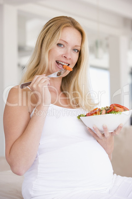 Pregnant woman with bowl of salad smiling