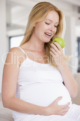 Pregnant woman eating apple and smiling