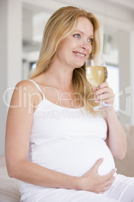 Pregnant woman with glass of white wine smiling