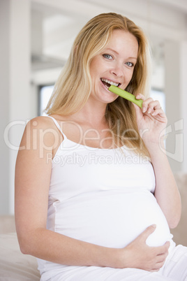 Pregnant woman eating celery and smiling