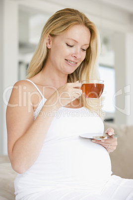 Pregnant woman with cup of tea smiling