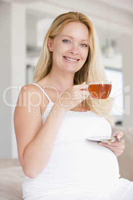 Pregnant woman with cup of tea smiling