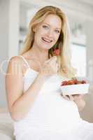 Pregnant woman with bowl of strawberries smiling