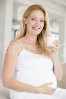 Pregnant woman with glass of milk smiling