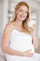 Pregnant woman with glass of milk smiling