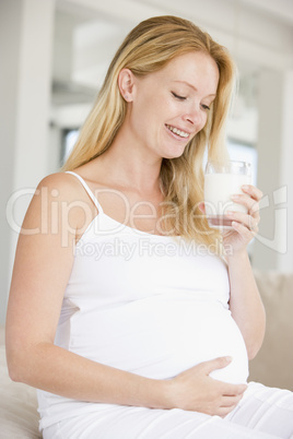 Pregnant woman with glass of milk smiling