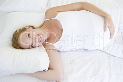 Pregnant woman lying in bed smiling