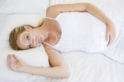 Pregnant woman lying in bed smiling