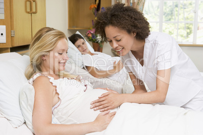 Nurse checking pregnant woman's belly and smiling