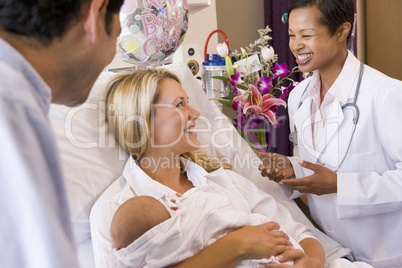 New parents with baby talking to doctor and smiling